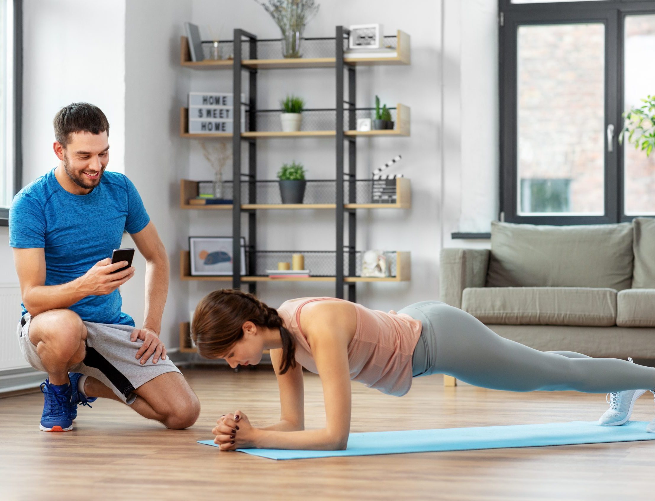 woman with personal trainer doing plank at home